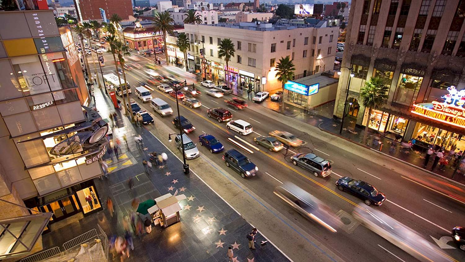 A nighttime view of a busy street with cars and palm trees.