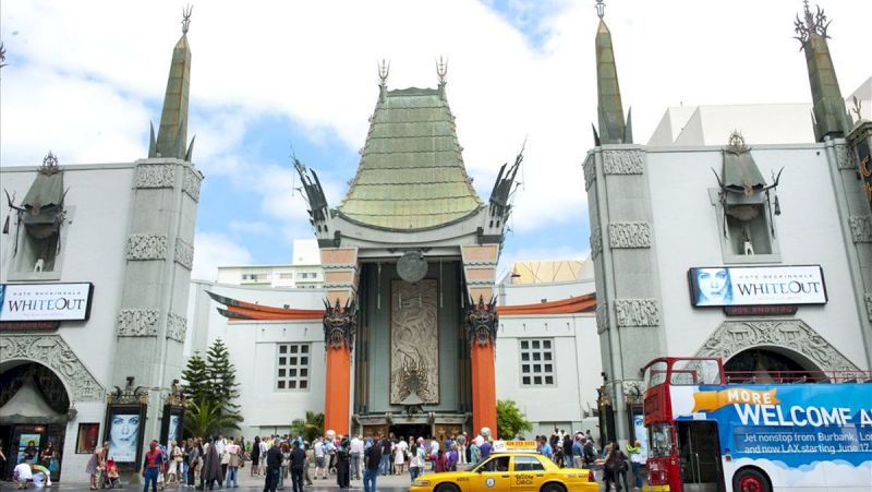 A large white building with a pagoda-style roof and a crowd of people in front of it.