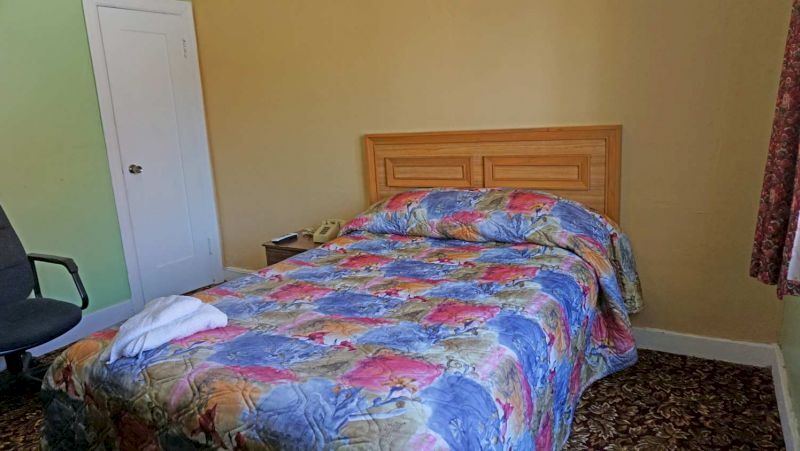 A single bed with a floral comforter and a wooden headboard in a small room.